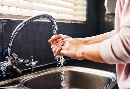 A healthy lifestyle starts with washing your hands regularly. Cropped shot of an unrecognizable woman washing her hand in the kitchen sink.