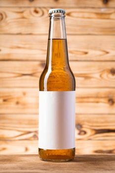 Blank label on the beer bottle on wooden background.