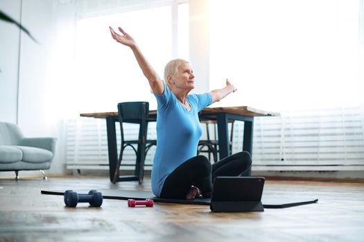 elderly woman starting fitness gymnastics with an online trainer.