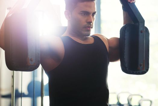Cropped shot of a handsome young sportsman working out with an exercise machine in a gym.