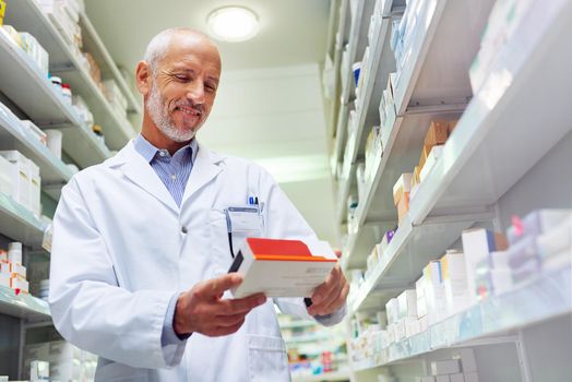 Hes meticulous when it comes to medicinal management. Shot of a mature pharmacist doing inventory in a pharmacy.
