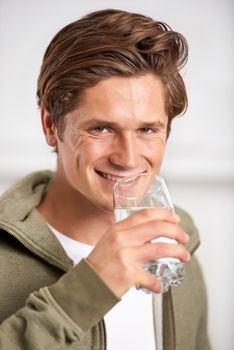 Keeping hydrated. A young man drinking a glass of water.