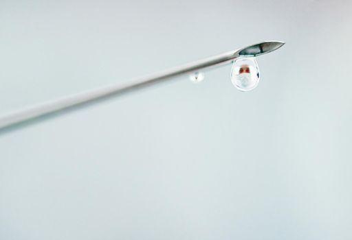 The face behind a clinical breakthrough. Shot of a surgical needle with medication dripping from it.