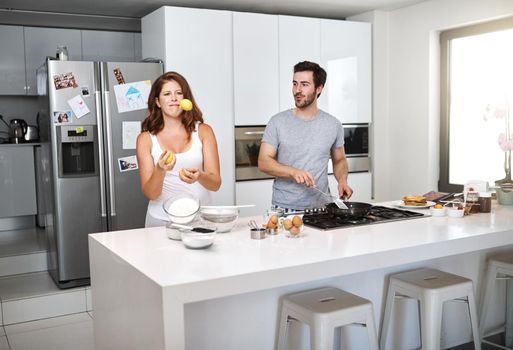Switching roles doesnt make a difference when united. Shot of a happy young couple preparing breakfast in the morning.
