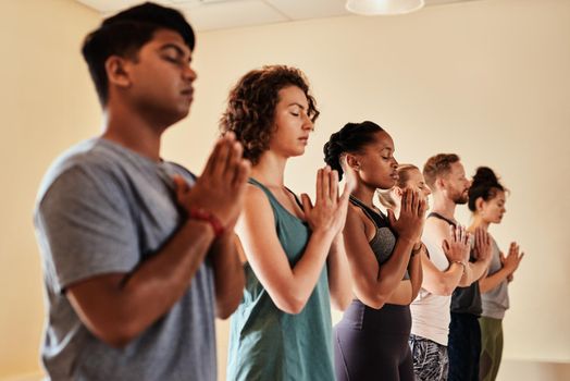 Yoga is a work of heart. Shot of a group of young men and women meditating in a yoga class.