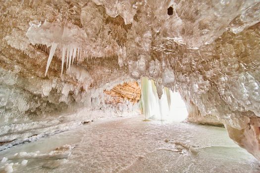 Beautiful pure and clear icicles covering ceiling of ice cave on lake