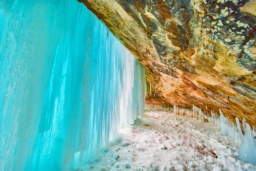 Stunning blue sheet of ice covering entrance to cavern in winter