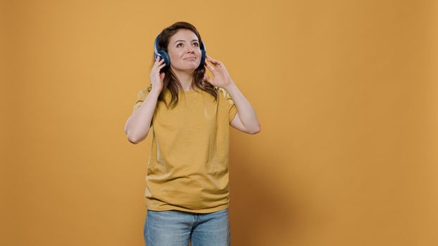 Portrait of casual woman with wireless headphones listening to upbeat music and dancing alone