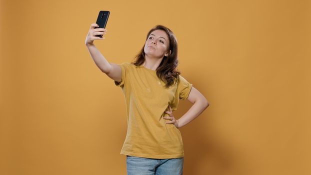 Portrait of woman using smartphone to take a selfie feeling confident and beautiful striking multiple poses