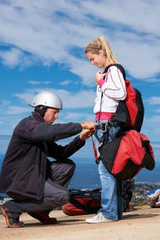 Making sure that everythings tight enough. A paraglider being assisted by her instructor.