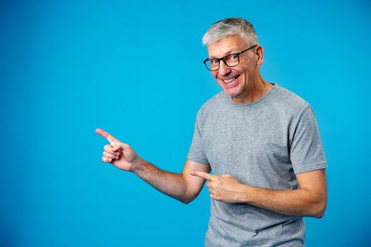 Happy mature man pointing finger to copy space