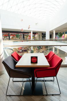 A table and soft chairs for visitors to the food court of a modern shopping center.