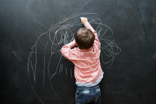 One day, this drawing will sell for millions. A young boy drawing on a blackboard.