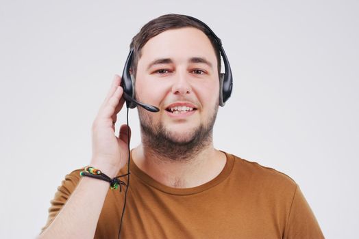 Customer service with a smile. Studio portrait of a handsome young male customer service representative wearing a headset against a grey background.