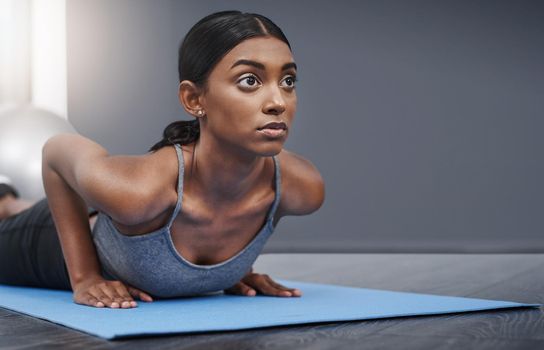 Laziness is also described as remaining in your comfort zone. Shot of an attractive young woman busy exercising on her gym mat at home.