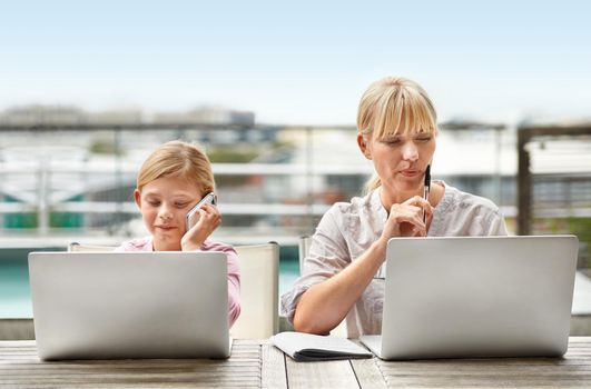 Present and future businesswomen. Shot of a young girl and her mother using laptops side by side.