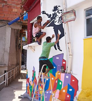 Decorating their city. Shot of two young graffiti artists painting a design on a wall.