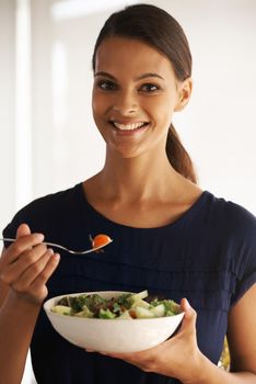 I nourish my body with the best. A beautiful young woman eating a bowl of salad at home.