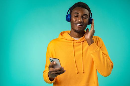 Happy black man listening to music on phone with headphones in studio