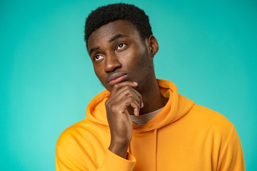 Young African American man isolated on mint background thinking and looking up
