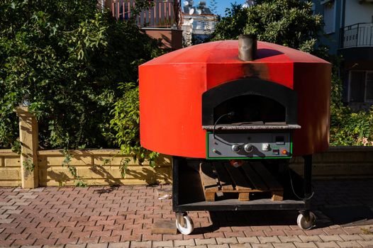 Large domed red metal outdoor pizza oven.