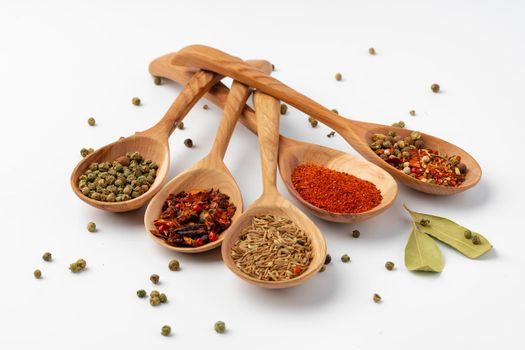 Colorful spices in the wooden spoons on white background.