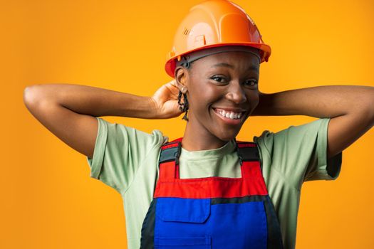 Young african american woman wearing architect hardhat against yellow background