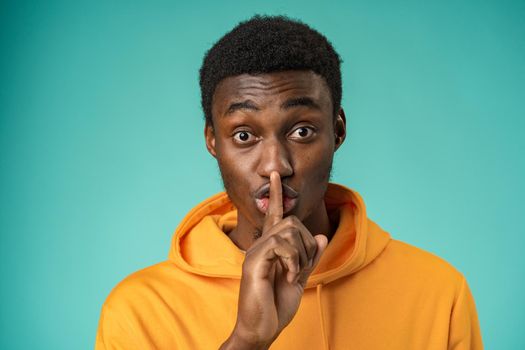 Black man showing silence gesture with finger on his lips