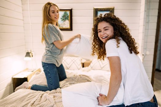 Two girl friends having pillow fight in bedroom