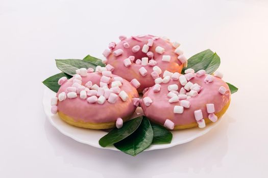 Colorful frosted pink doughnut. Assorted donuts. Pink glazed and sprinkles donuts. Rotating shot of white tasty delicious sweet donut with colorful sprinkles on white background. Dessert