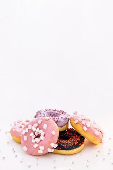 Donuts with different fillings on the white table. Assortment of donuts of different flavors. Chocolate frosted, pink glazed and sprinkles donuts