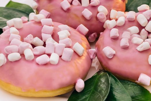 Close-up of a delicious round donuts covered with sweet icing rotates on a bright background. Sweet dessert pink donuts