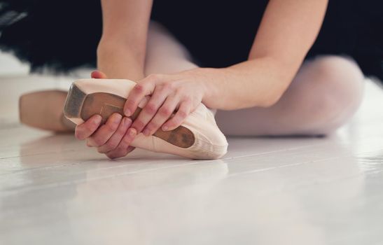 Apply pressure then move on. Shot of an unrecognizable ballet dancer putting on her pointe shoes.