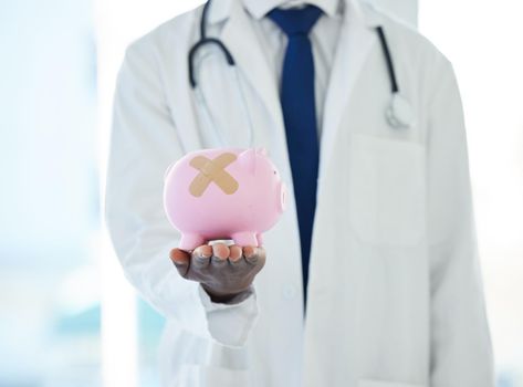 Need some debt counselling Visit our money clinic. Shot of an unrecognisable doctor holding a piggybank with a band aid covering it.