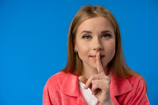 Young pretty woman showing silence gesture over blue background