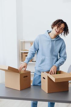 guy with curly hair unpacking with box in hand moving Lifestyle