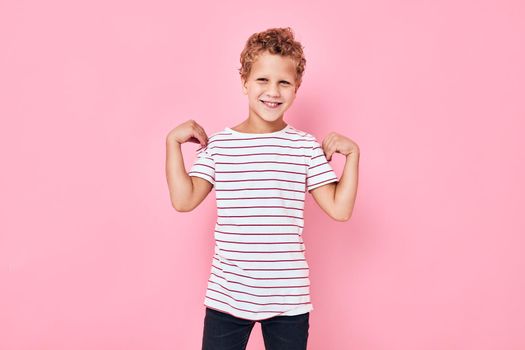 boy with curly hair childhood smile plays pink color background
