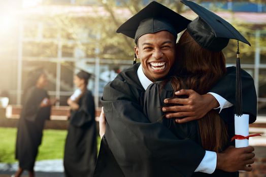 Together forever in love and education. Portrait of a happy young man and woman hugging on graduation day.