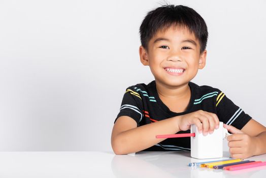Little cute kid boy 5-6 years old smile using pencil sharpener while doing homework