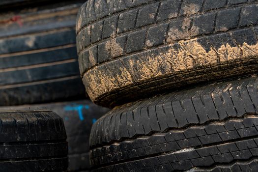 Stack of old tires. Pile of used tires. Black rubber tire of car. Dirty used tyres. Closeup old tyres waste for recycle. Closeup tread of an old dirty tyre. Change car tire for safety concept.