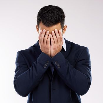 Studio shot of a young businessman covering his face against a white background.