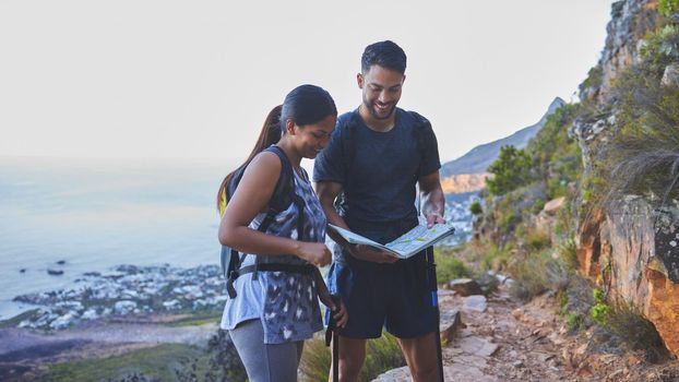 This is so helpful to plot out our hike path. Shot of a young couple using a guide book to complete a hike in a mountain range.
