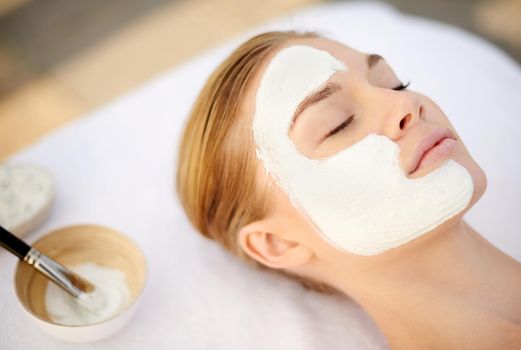 Indulging in a deep cleansing masque. Shot of a young woman getting a facial at a spa.