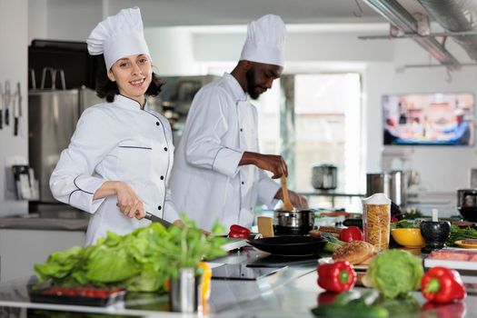 Professional cooks wearing cooking uniforms preparing fresh vegetables garnish for delicious dinner dish