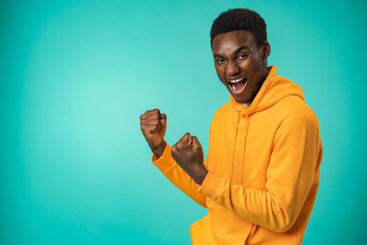 Portrait of overjoyed black man celebrating success in studio