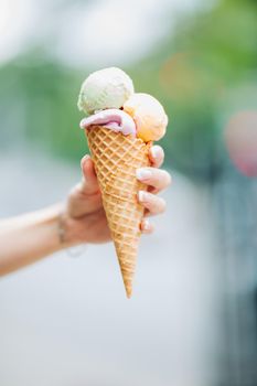 Tender woman's hand keeping delicious colorful ice cream.