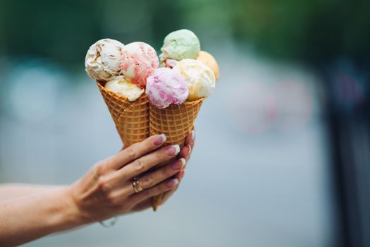 Crop of woman's hand holding delicious colorful ice cream.