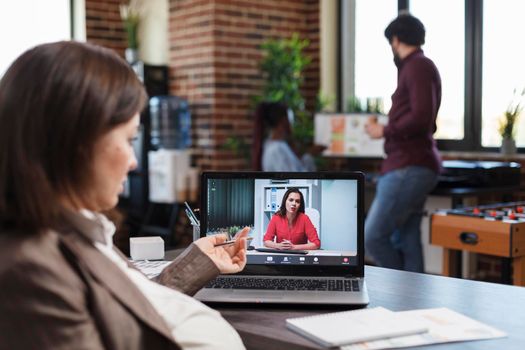 Financial company pregnant employee in teleconference videocall with agency colleague discussing about business plan. Business woman conferencing with project manager about necessity of hiring people.