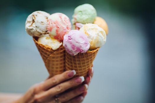 Crop of woman's hand holding delicious colorful ice cream.