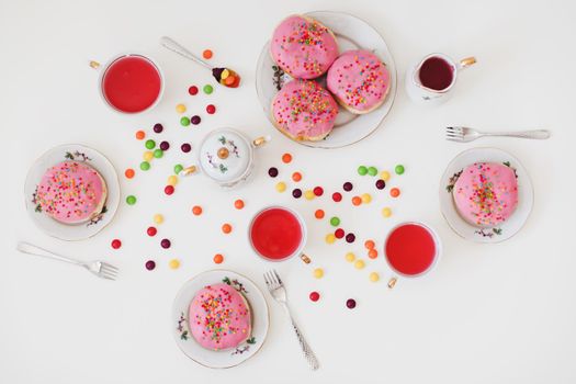 holiday, birthday party composition with colorful pink glazed donuts on white table, flatlay top view